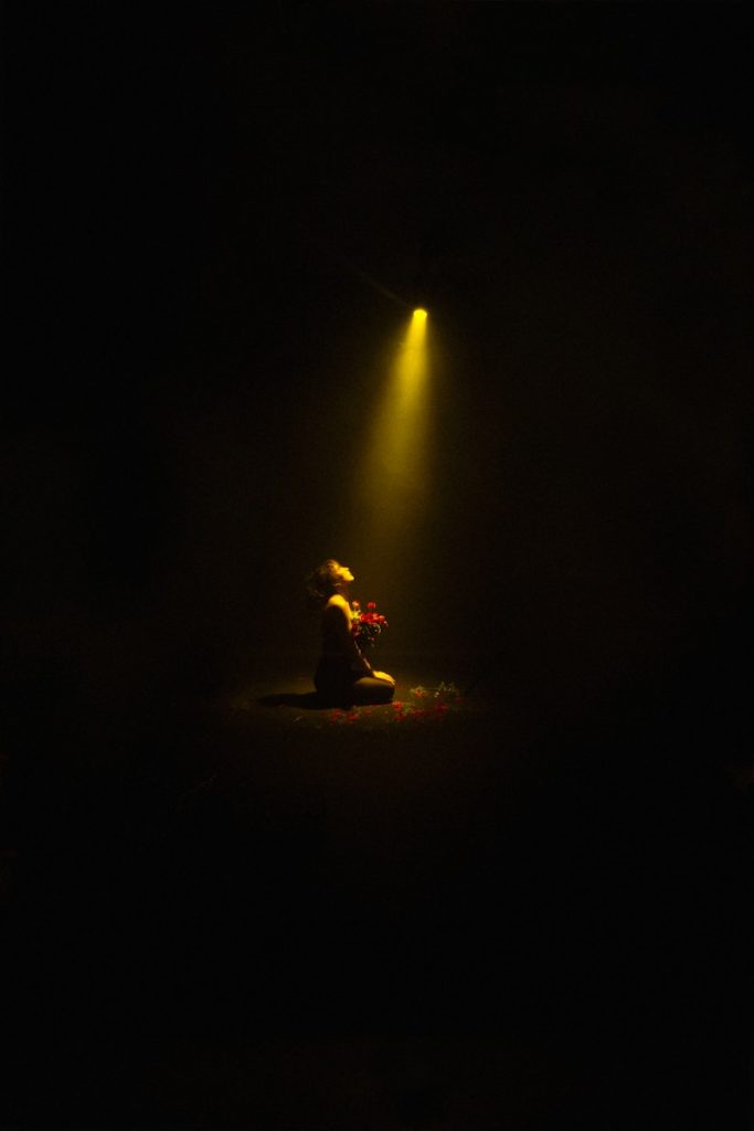 A person sitting on the ground under a light